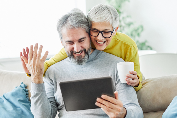 couple on couch looking at laptop and high-fiving about Fidium expansion